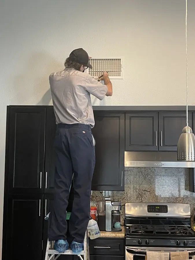 Technician inspecting an air vent during HVAC service in East Lake-Orient Park